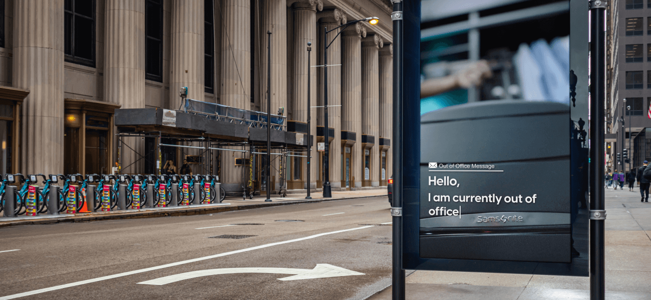 Samsonite digital out-of-home ad featuring an “out of office” message, displayed on a busy downtown street.