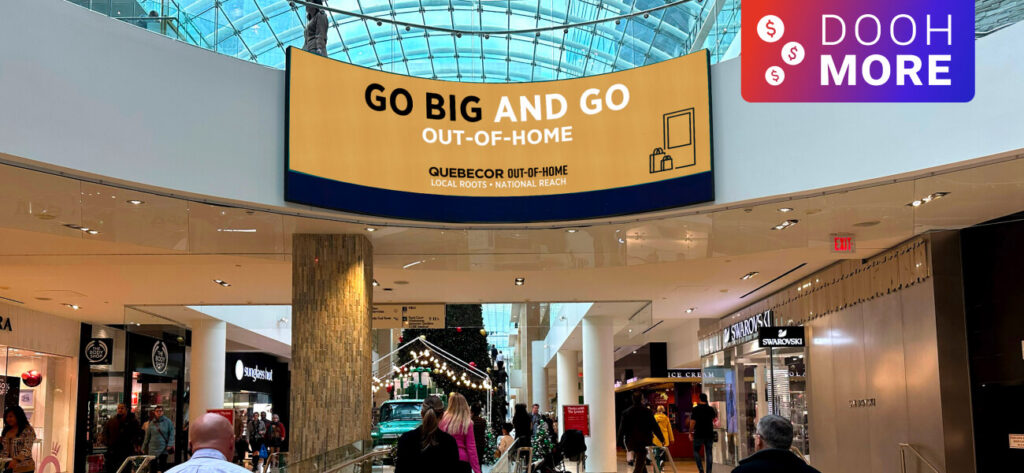 Digital advertising screens displayed above storefronts inside a shopping mall.