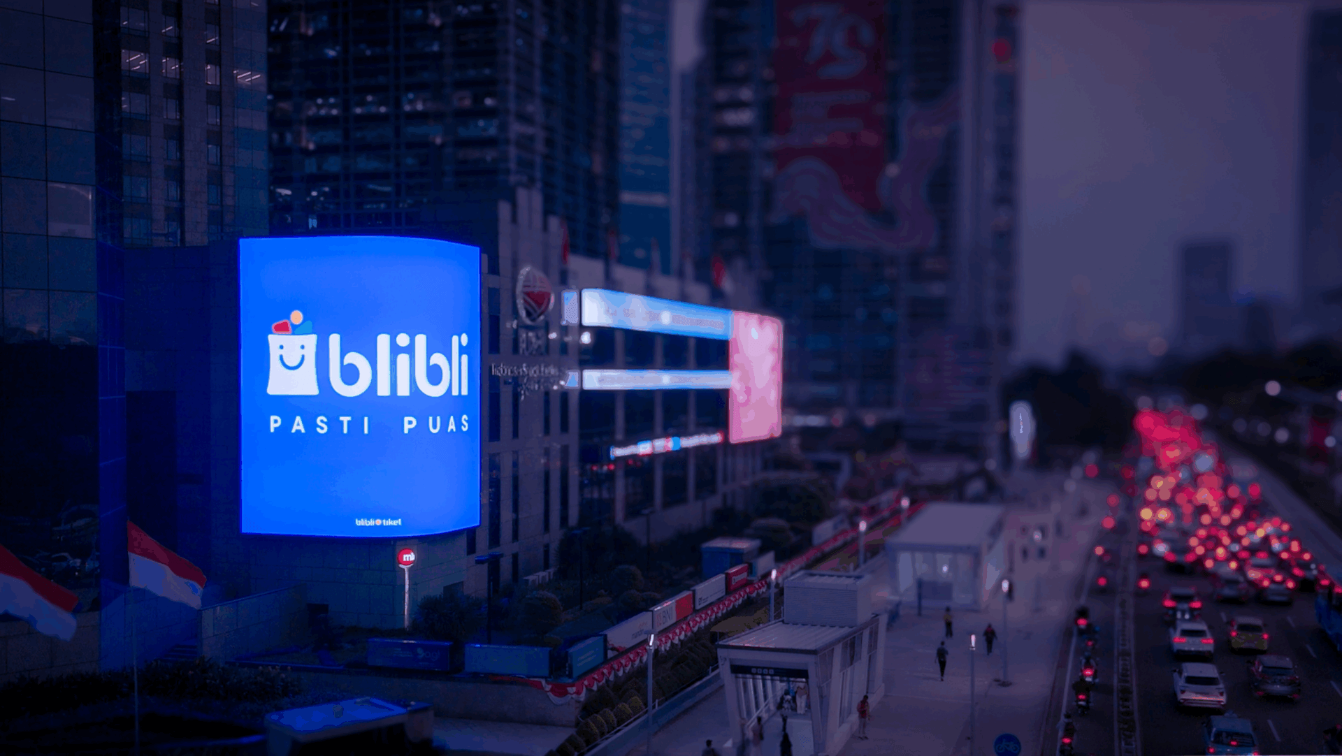 Digital out-of-home billboard illuminating a busy urban street at night with heavy traffic in Indonesia.