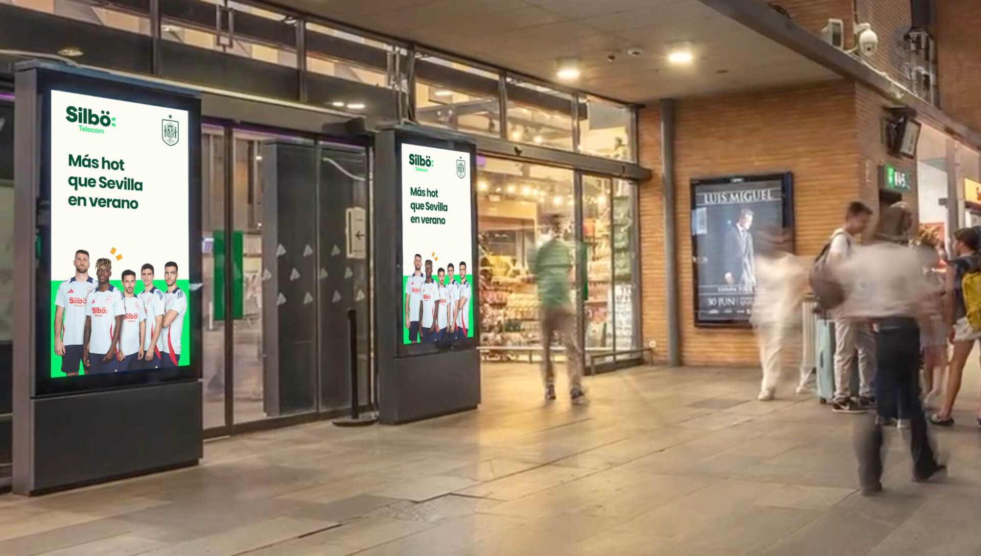Silbö Telecom digital out-of-home ads featuring Sevilla football players displayed outside a busy shopping centre.