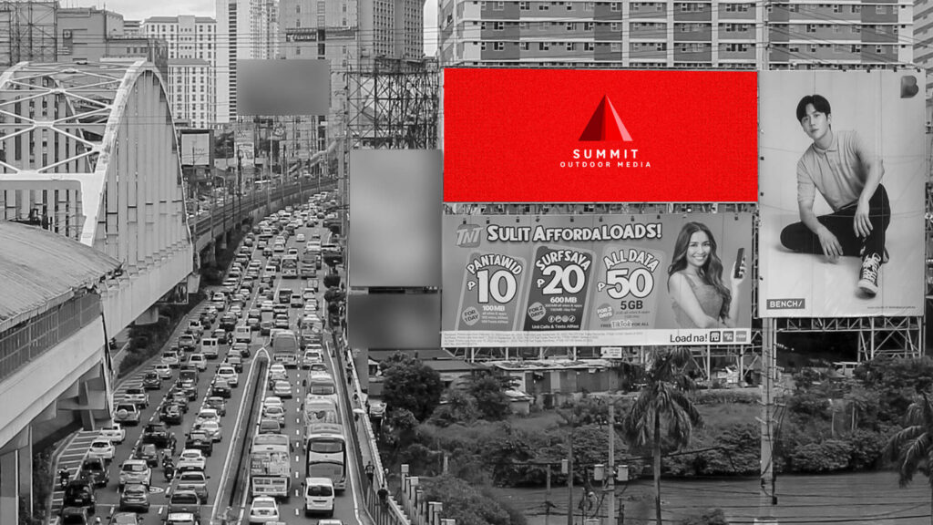 Heavy city traffic passing large roadside billboards, including a red Summit Outdoor Media display.