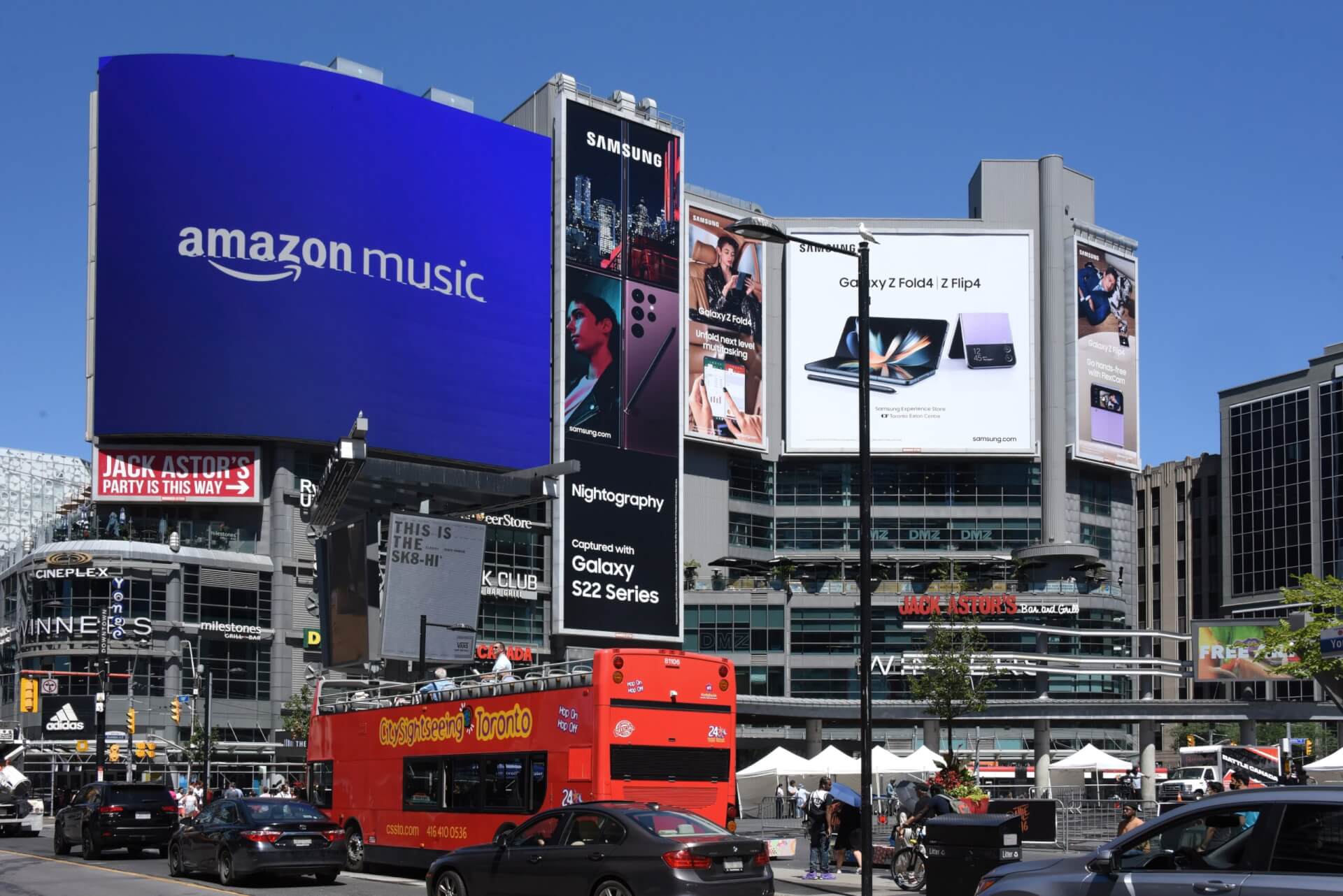 Large Amazon Music and Samsung digital billboards displayed at a busy urban intersection in Toronto.