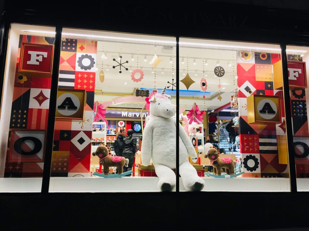 FAO Schwarz storefront featuring colorful geometric window displays and a large plush polar bear.