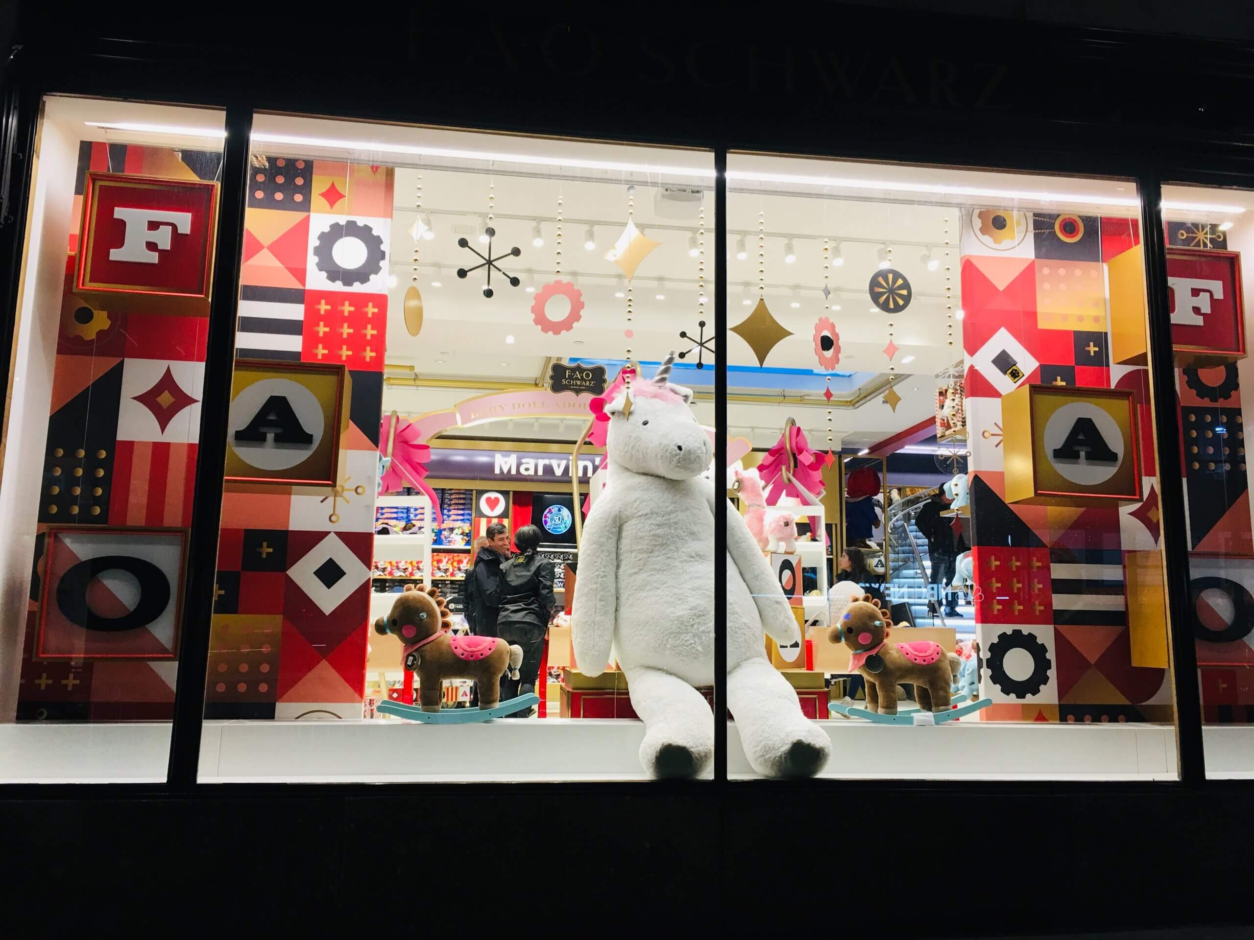 FAO Schwarz storefront featuring colorful geometric window displays and a large plush polar bear.