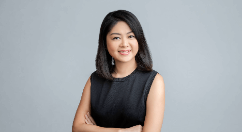 A woman smiling against a grey background.