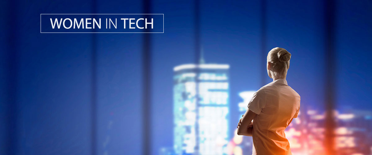 Woman looking out at a blurred cityscape with the text “Women in Tech.”